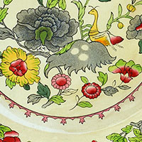Cropped image. We can see a print of a mix of flowers, leaves, and a bird on a pale yellow background.