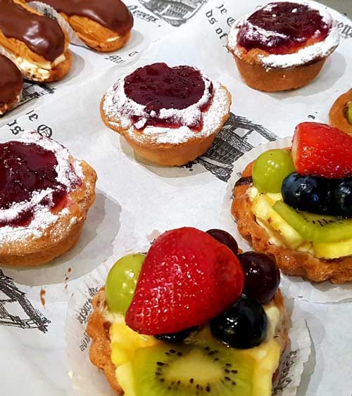 Several individual cakes covered in fruit and cream.