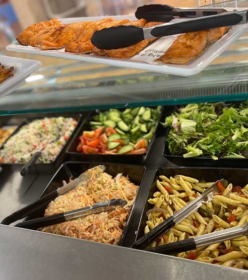 A range of colourful salads with tongs ready to dish them out.