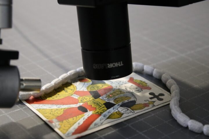 A close up of a coloured playing card underneath a piece of scientific equipment.