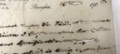 A close up of a page with writing. The ink has burnt through the paper, leaving holes where the writing should be.