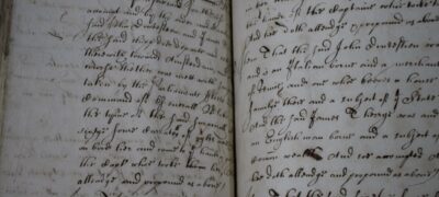 A close up of an open book filled with handwriting. The writing disappears into the centre of the book due to a tight binding.