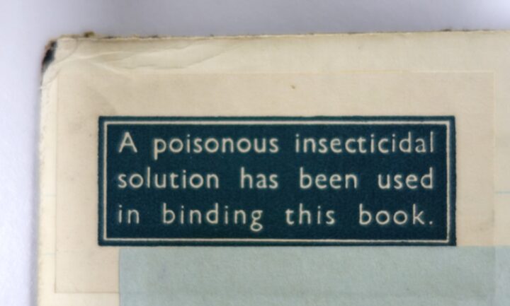 A green label indicating an insecticide solution has been applied to the binding of a book.
