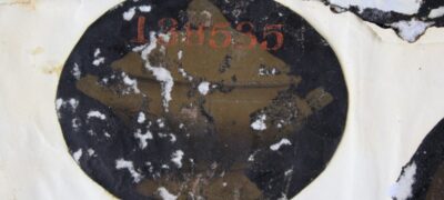 A close up image of an oval photograph of a ceramic pot on a black background. The surface of the photograph is cracked and flaking.