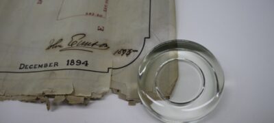 The corner of a map is torn and damaged, and is gently weighted down with a glass weight.
