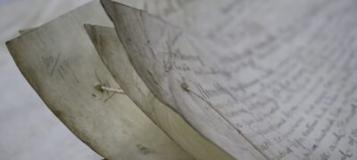 A close up of the corners of large sheets of paper, which are connected together with a thick sewing thread.