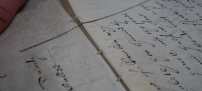A close up of sewing holding together two parchment sheets.