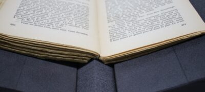 A close up image of a paperback book supported by two wedges and an arched spine insert.