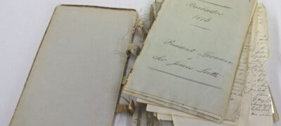 A badly damaged book on a table. The spine and sewing which held the pages together has fully detached. Pages are loose.