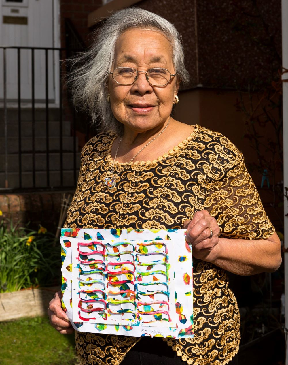An elderly lady holding the artwork she created