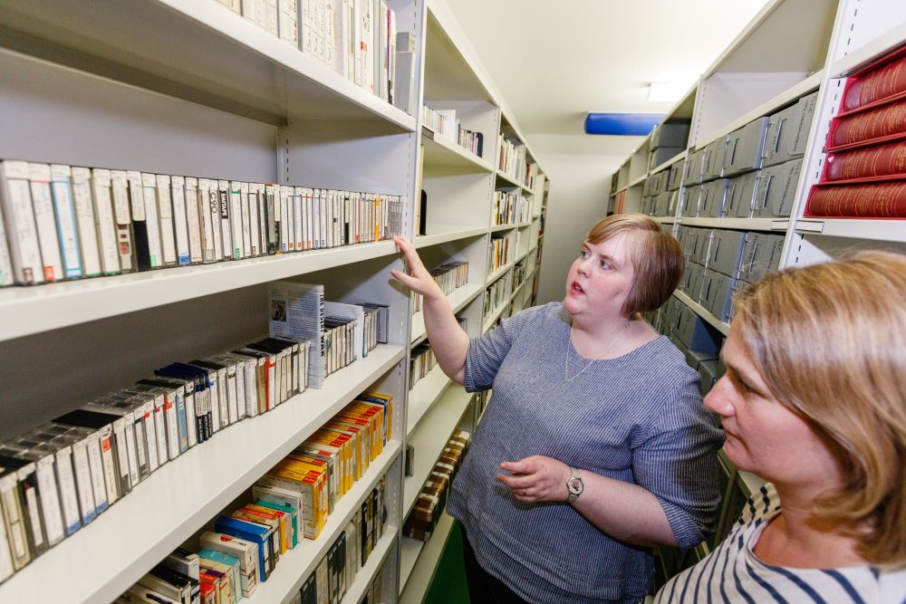 Two women looking at shelves of tape recordings