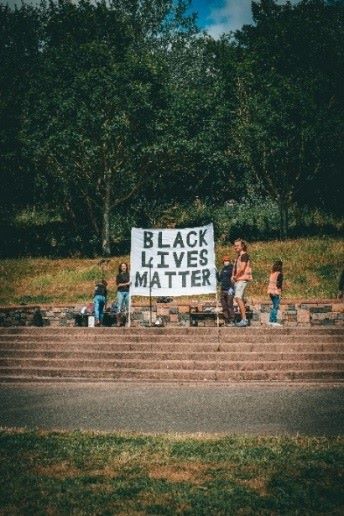 A small group of people standing outside with a Black Lives Matter banner