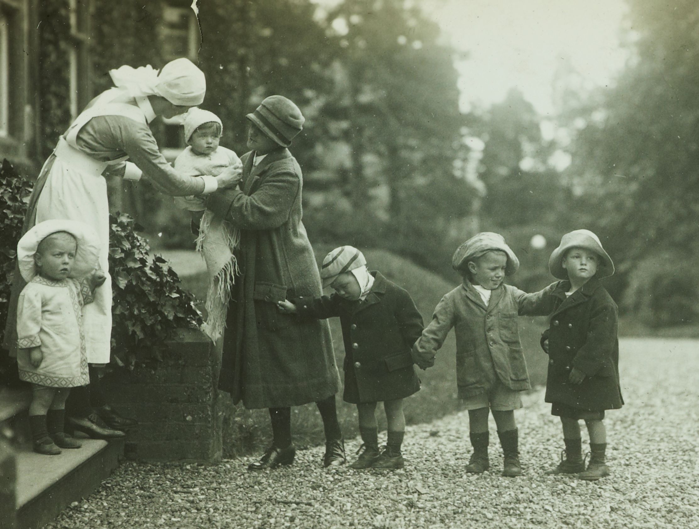 A black-and-white photograph of small children standing in a row outside