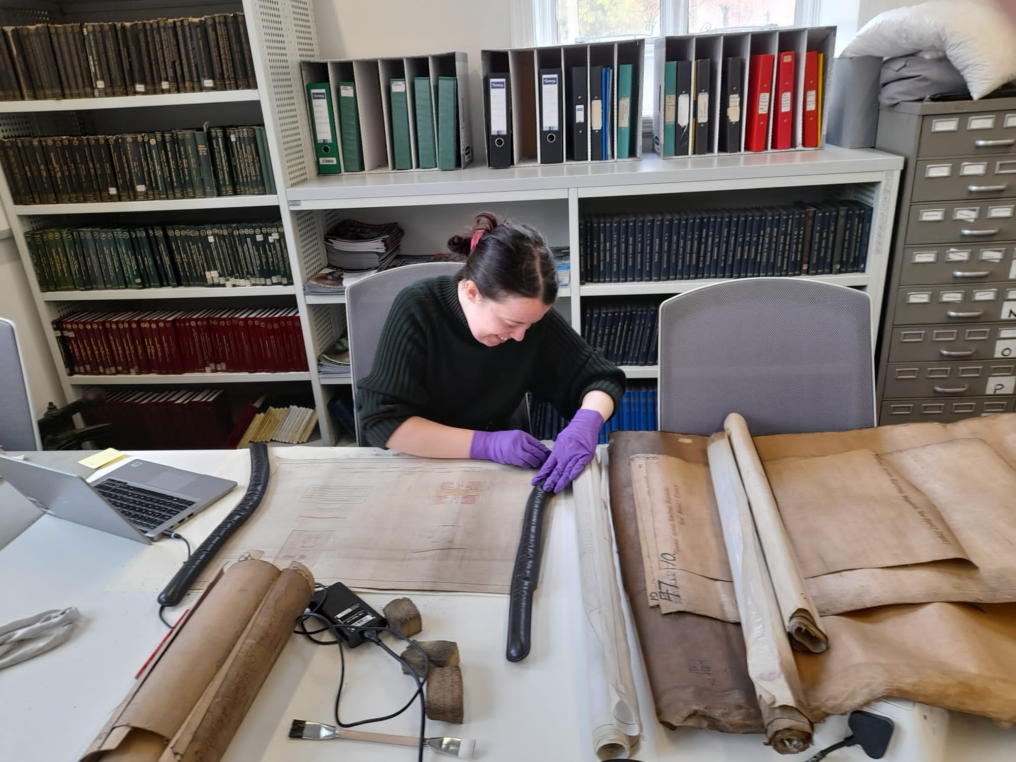 A person working with an old unrolled document on a desk