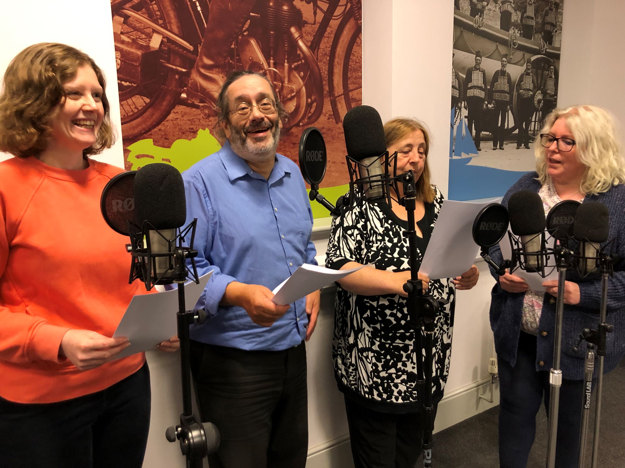 A group of four people standing around a set of microphones