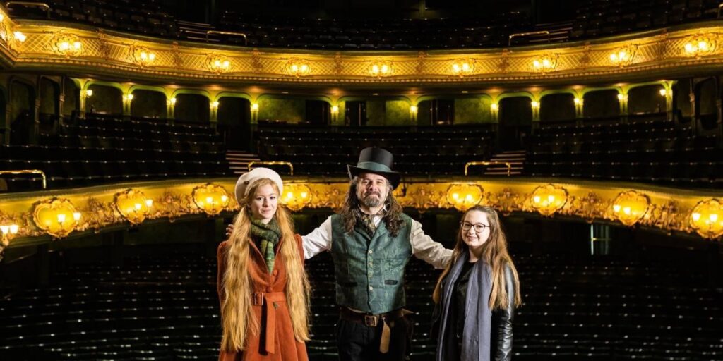 Image of actors in costume standing in front of the Theatre Royal and Royal Concert Hall auditorium