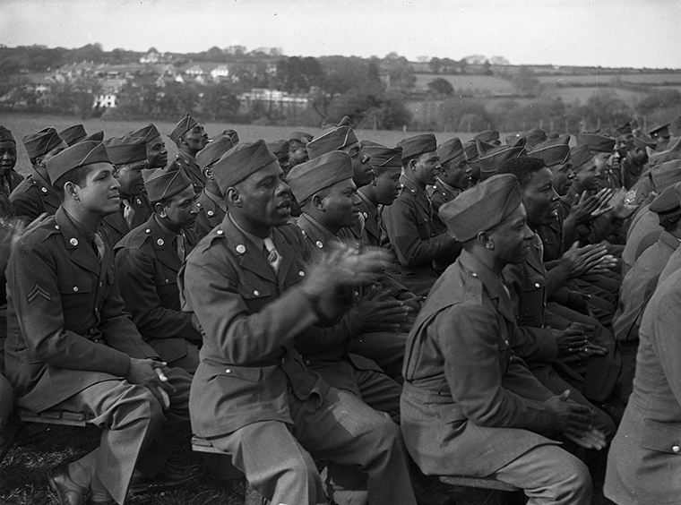 A seated audience of Black American soldiers, all in full uniform.