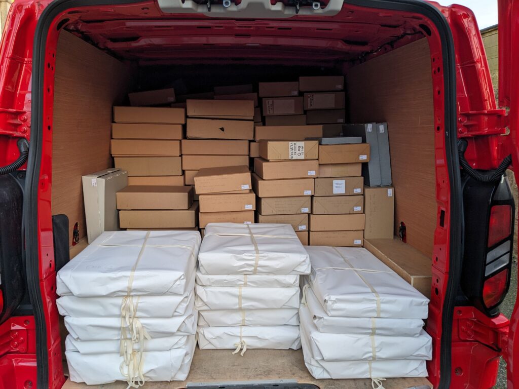 The back of an open red van holding dozens and dozens of neatly piled boxes.