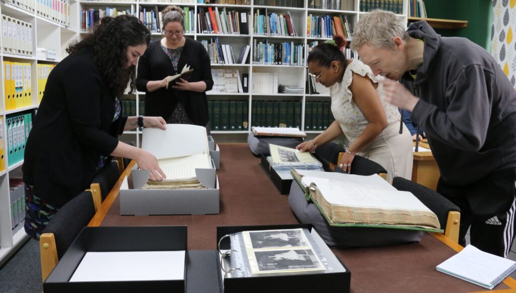 A group of people examine documents in a reading room.