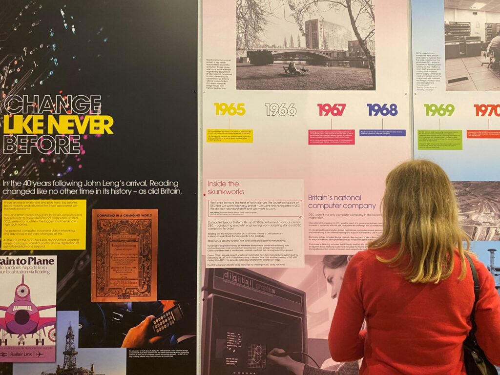 A person looks at a large and colourful exhibition wall display. This contains images and text.