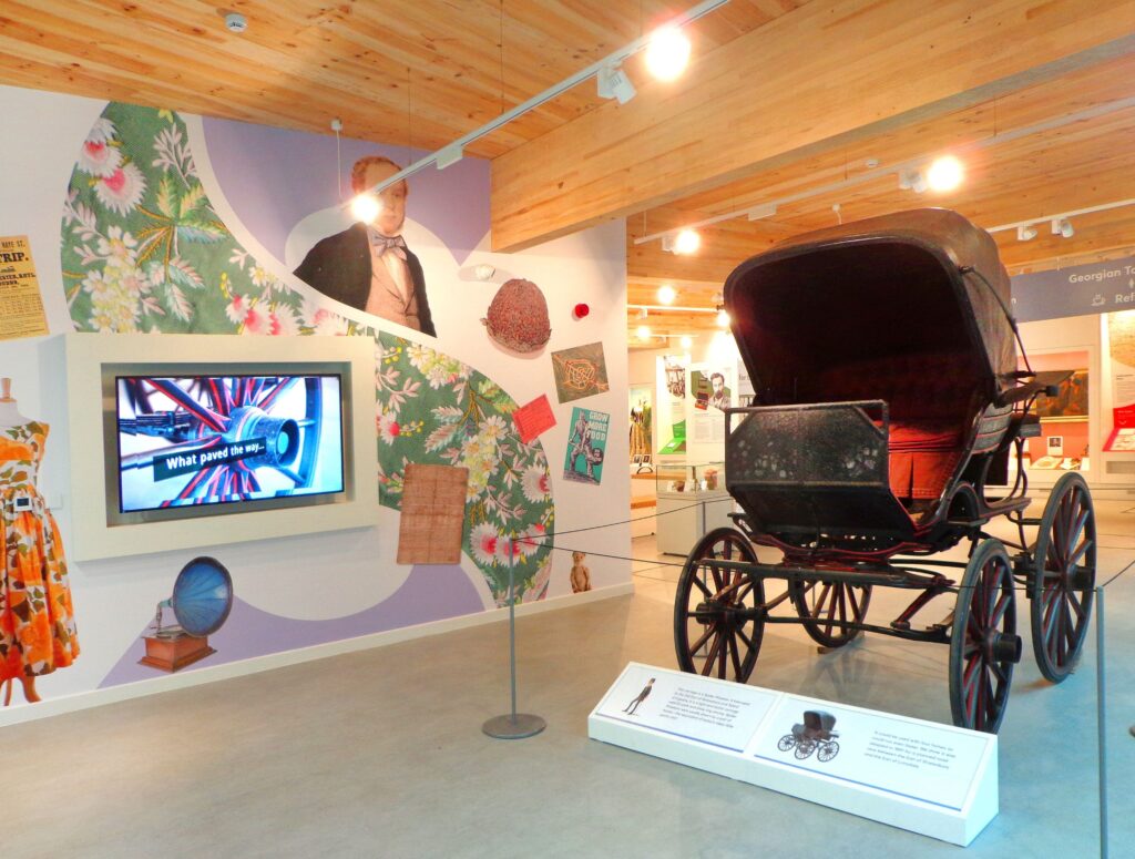 A large exhibition space displaying a buggy (with an explanatory placard in front of it) and an interactive screen.