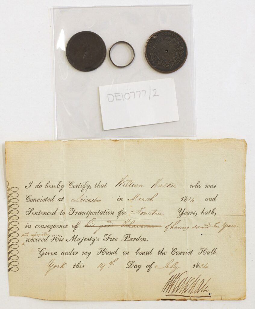 A small piece of paper detailing a pardon for a convict in the 1800s, accompanied by a keyring and coins above it.