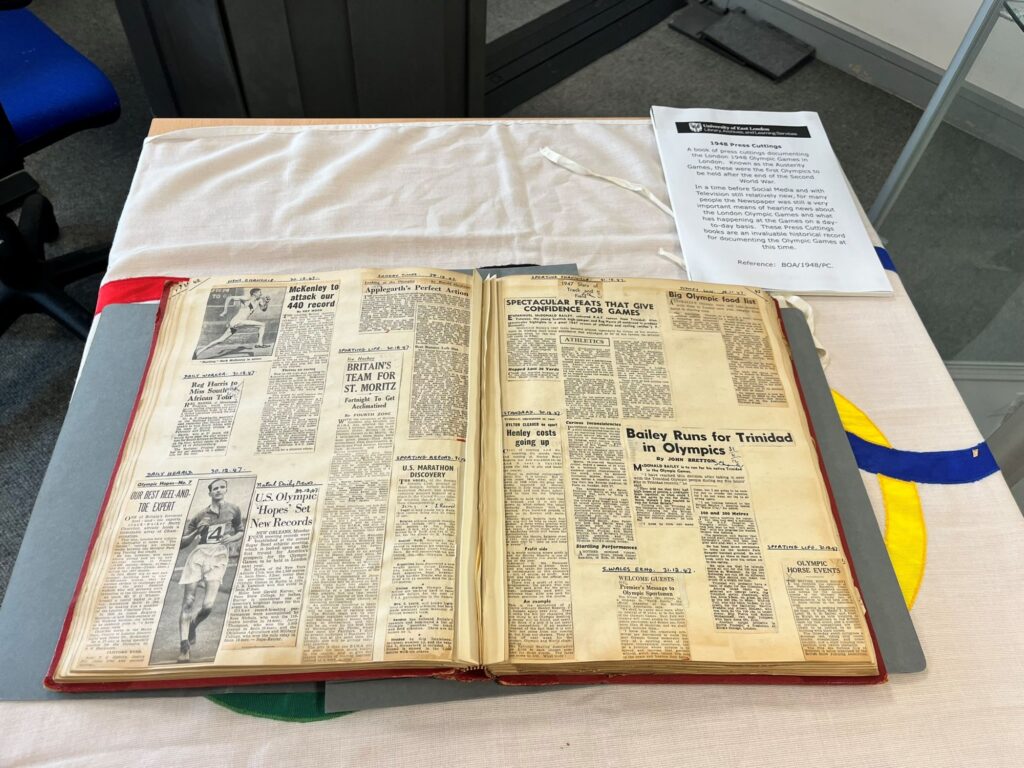 A large open scrapbook with cuttings of newspaper articles about athletics and the Olympics