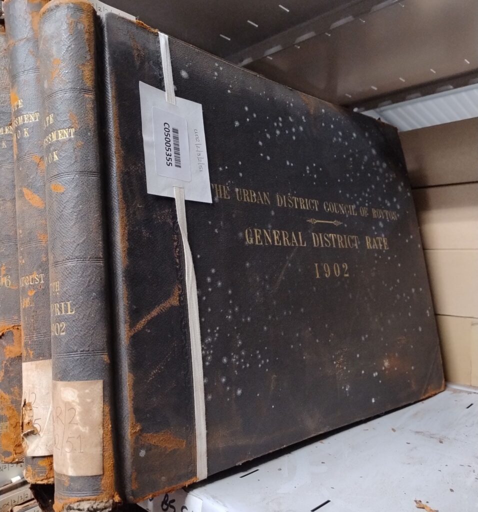 A close up of three books on a shelf that have deteriorated from mould.