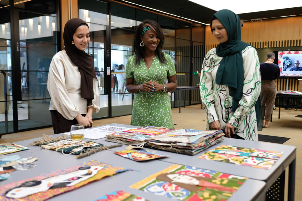 A group of three women looking at brightly coloured scrapbooks on a table