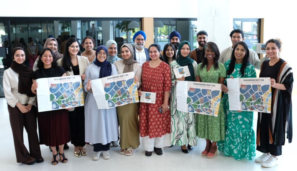 A large group of people standing together, with the front row holding up maps