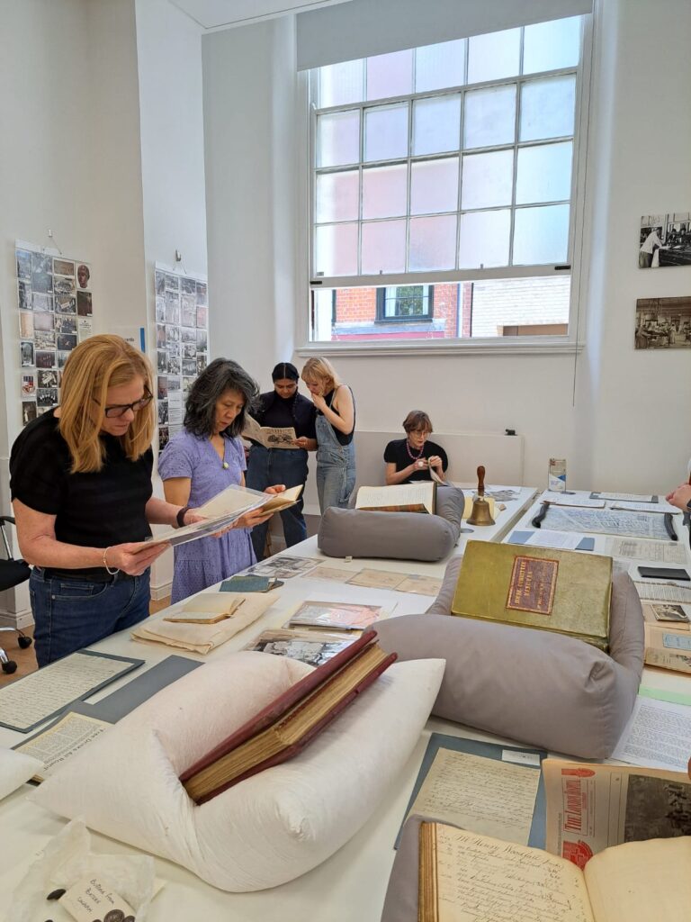 Four people look at archive material displayed on a table