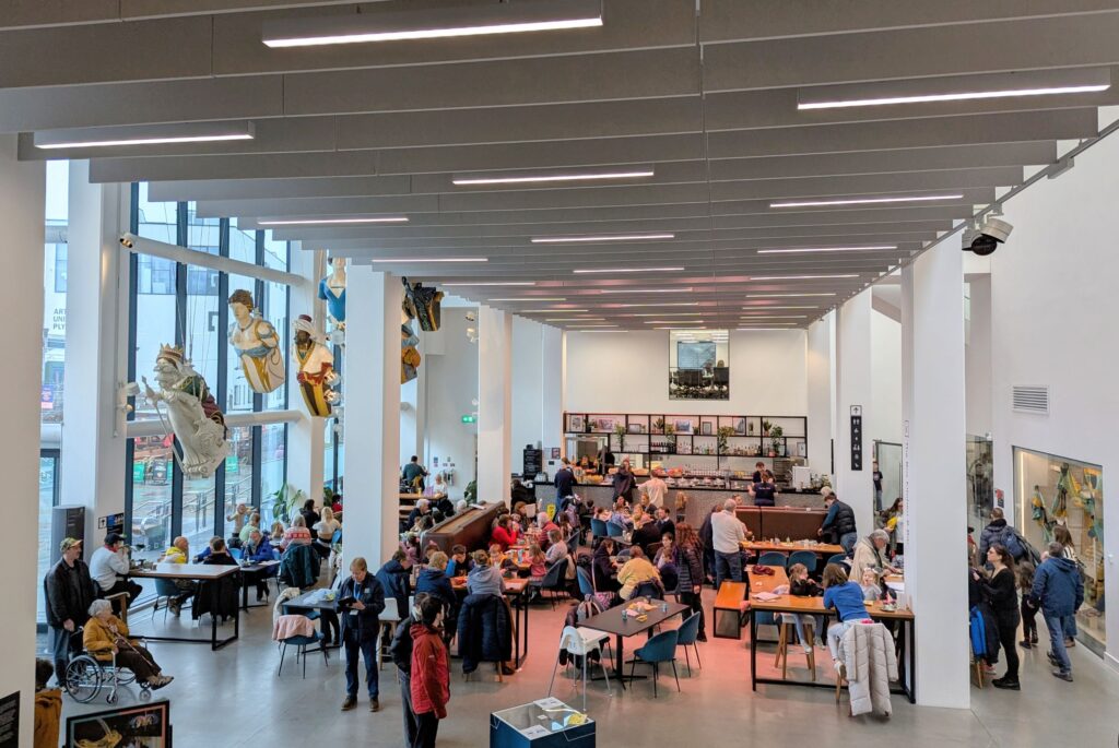 A large, open-plan dining space, full of people of all ages.