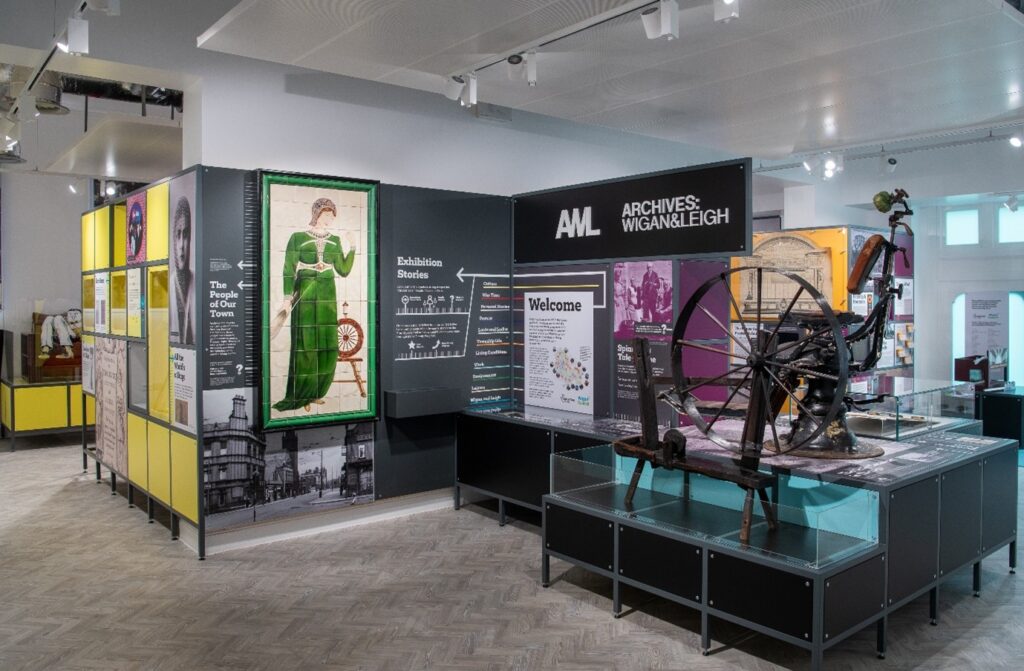 Various exhibition pieces are on display, including a tiled mural of a woman in a green dress.