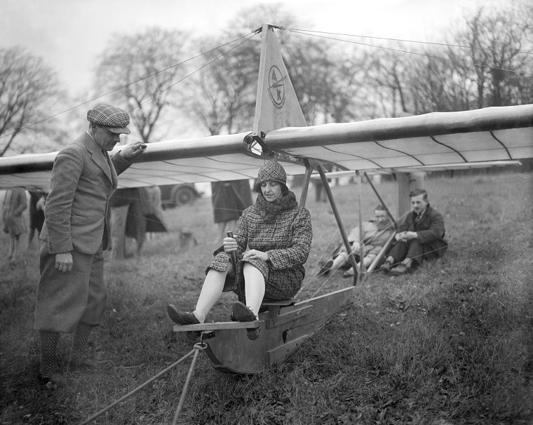 Black and white photo of Mary Bailey sitting in the seat of an open-air prototype aircraft.