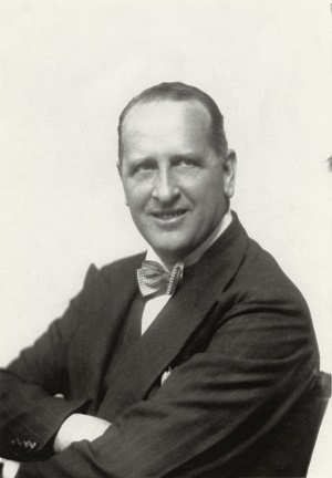 A black and white photo of Noel, side on, wearing a suit and bow tie.