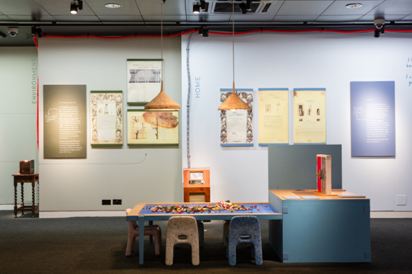 An image of the exhibition space showing a small lego play table, little chairs for children, with facsimile original designs of The National Archives displayed on the wall behind