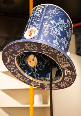 A picture of a top hat tilted on a stand, which is made of blue cyanotype with a small fan