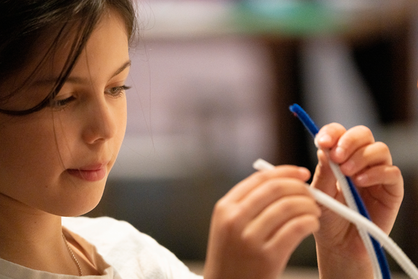 Photograph of little girl holding two cords about to create an invention
