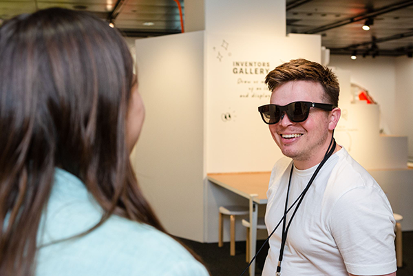 Photograph of child wearing XRAI glasses in the exhibition. The glasses are black and look like a pair of sunglasses.