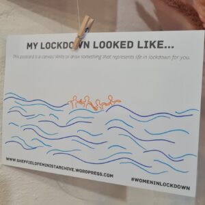 A white card hanging from a clothes peg. The top of the card reads 'my lockdown looked like' and the majority of space is taken up with an illustration of four figures holding hands in wave-stricken waters.