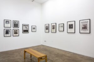 A white gallery space with several framed photographs lining the walls.