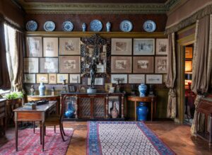 The drawing room of Sambourne House complete with framed photographs, carpets, vases, china plates and other trinkets