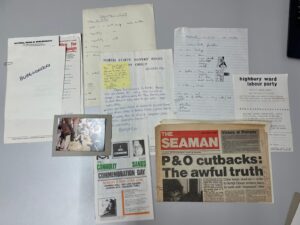 A collection of handwritten notes, documents and newspapers laid out on a table. The most prominent newspaper headline reads "P&O cutbacks: The awful truth".