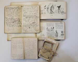 A collection of handwritten notebooks and illustrations laid out on a white table.