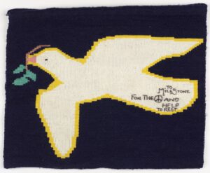 Embroidery depicting a yellow bird with a tiny branch in its mouth.